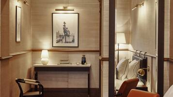 Una habitación de hotel con cama, escritorio, silla y espejo.