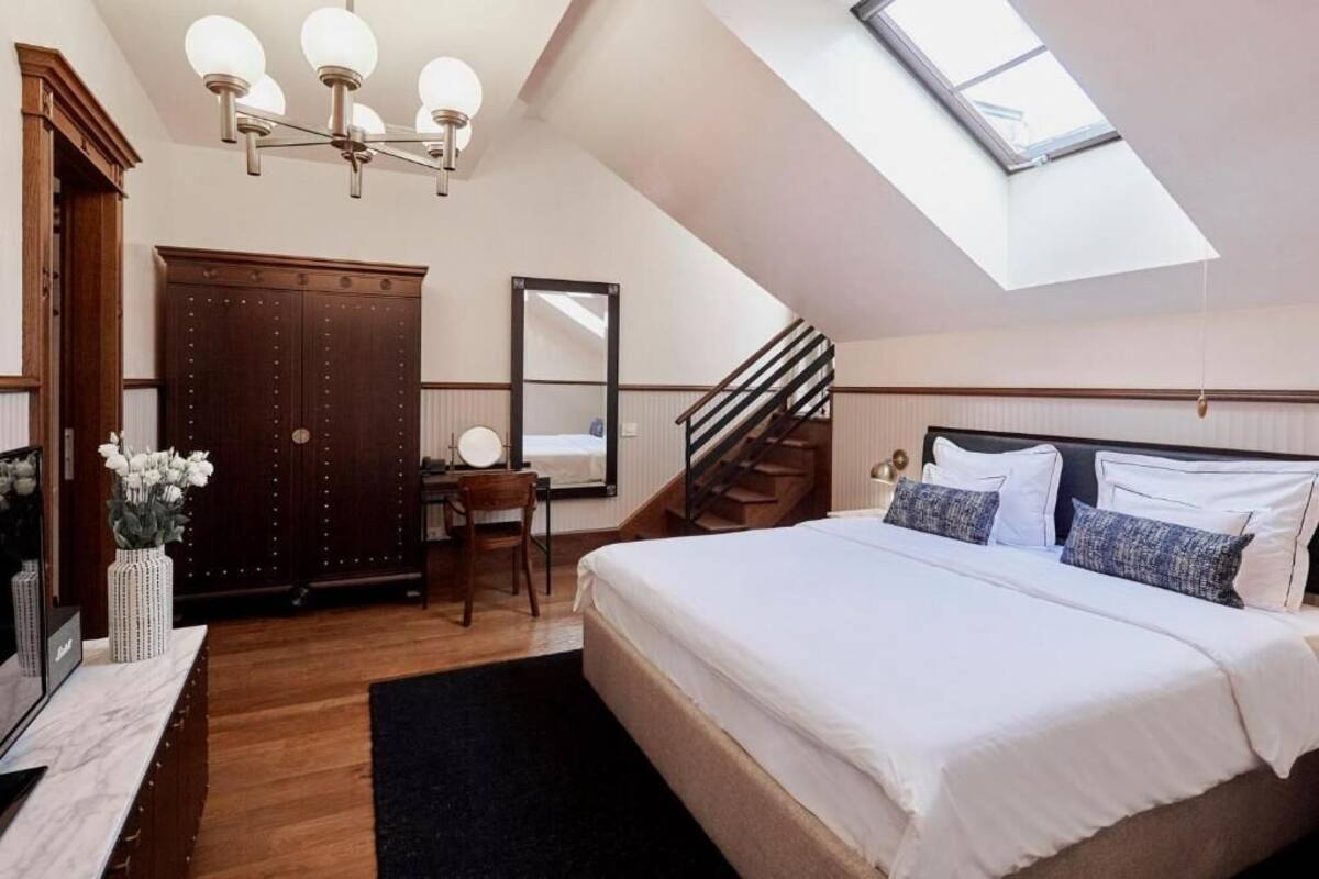 Un dormitorio con tragaluz, una cama, un escritorio, una silla, un armario y una escalera.