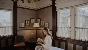 A room with a bed, a chair, a lamp, and framed pictures on the wall. - Callas House (Budapest)