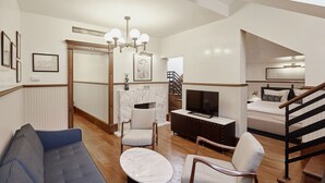 A modern living room with a sofa, chairs, a coffee table, a TV, and a staircase. - Callas House (Budapest)