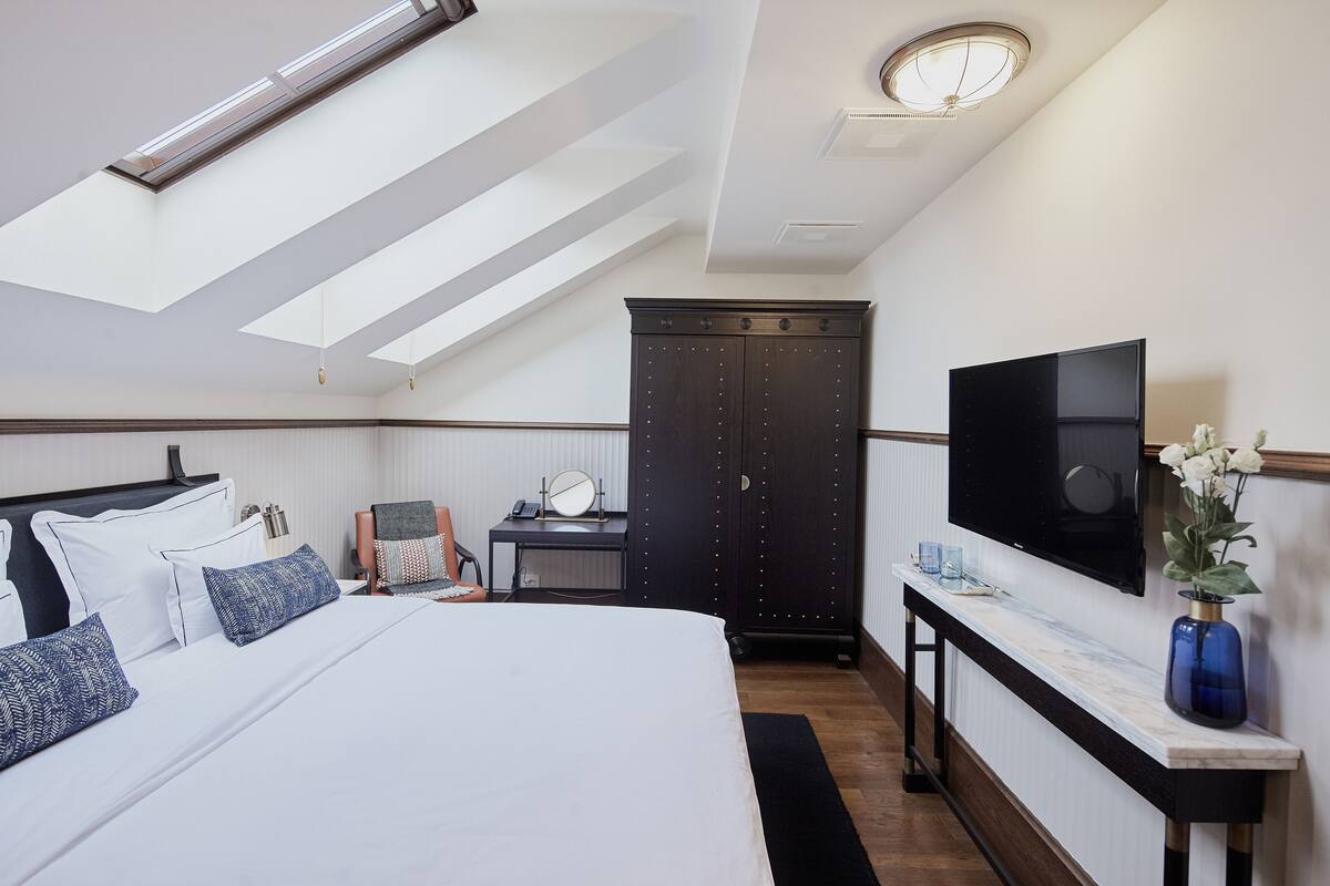 Una habitación de hotel moderna con una cama grande, un escritorio, un armario y un televisor.