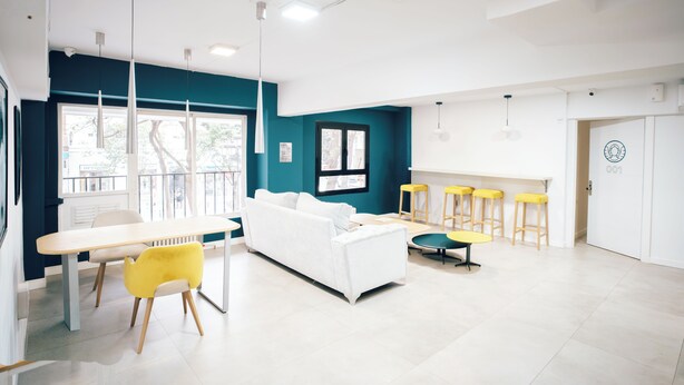 Un intérieur moderne avec un canapé blanc, des chaises jaunes, une table blanche et un mur d’accent de couleur turquoise.