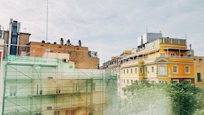 Un immeuble à plusieurs étages, avec des échafaudages, une façade en briques et un bâtiment jaune doté de balcons.