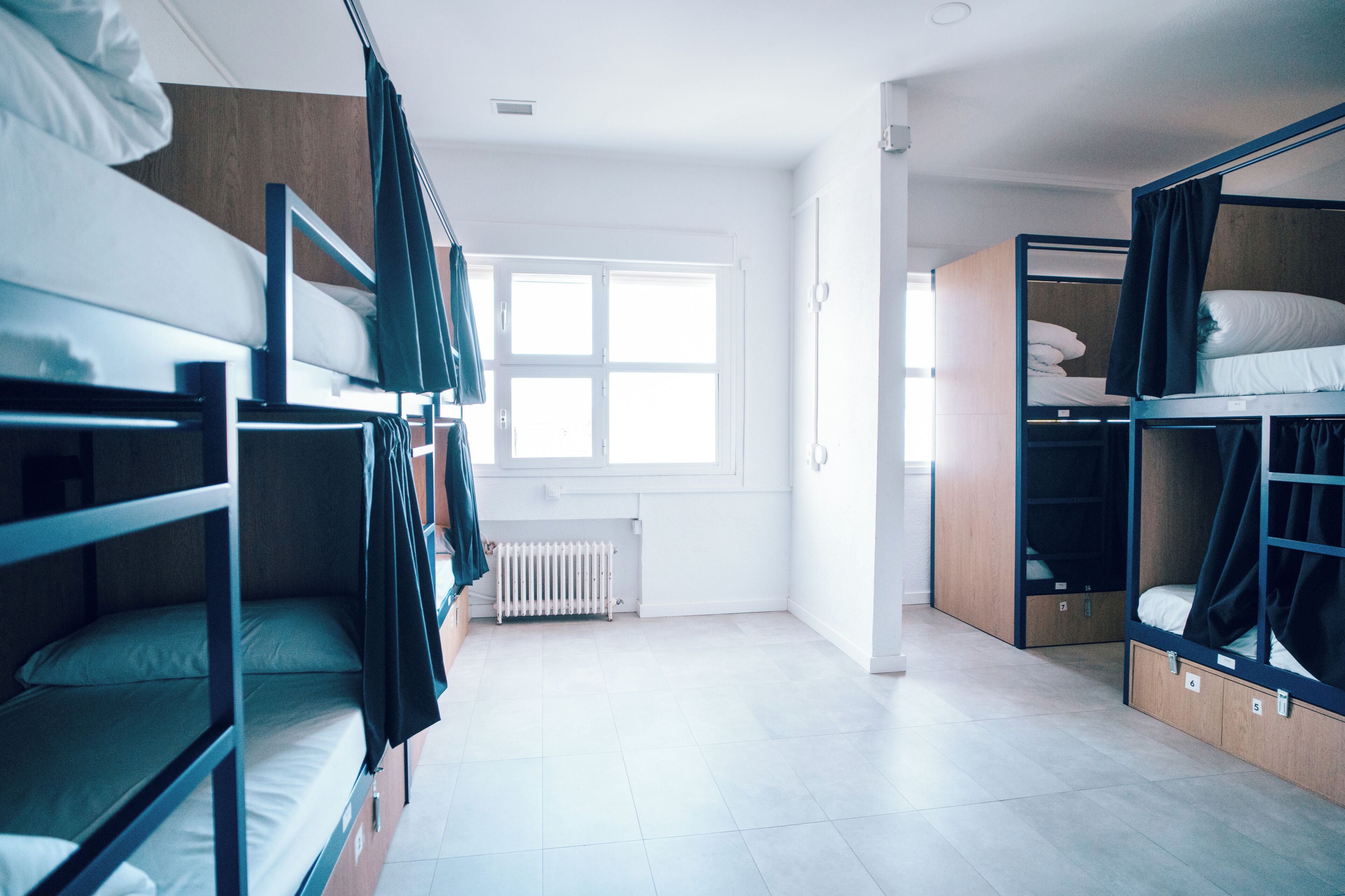 A dormitory room with bunk beds, a radiator, and a window.