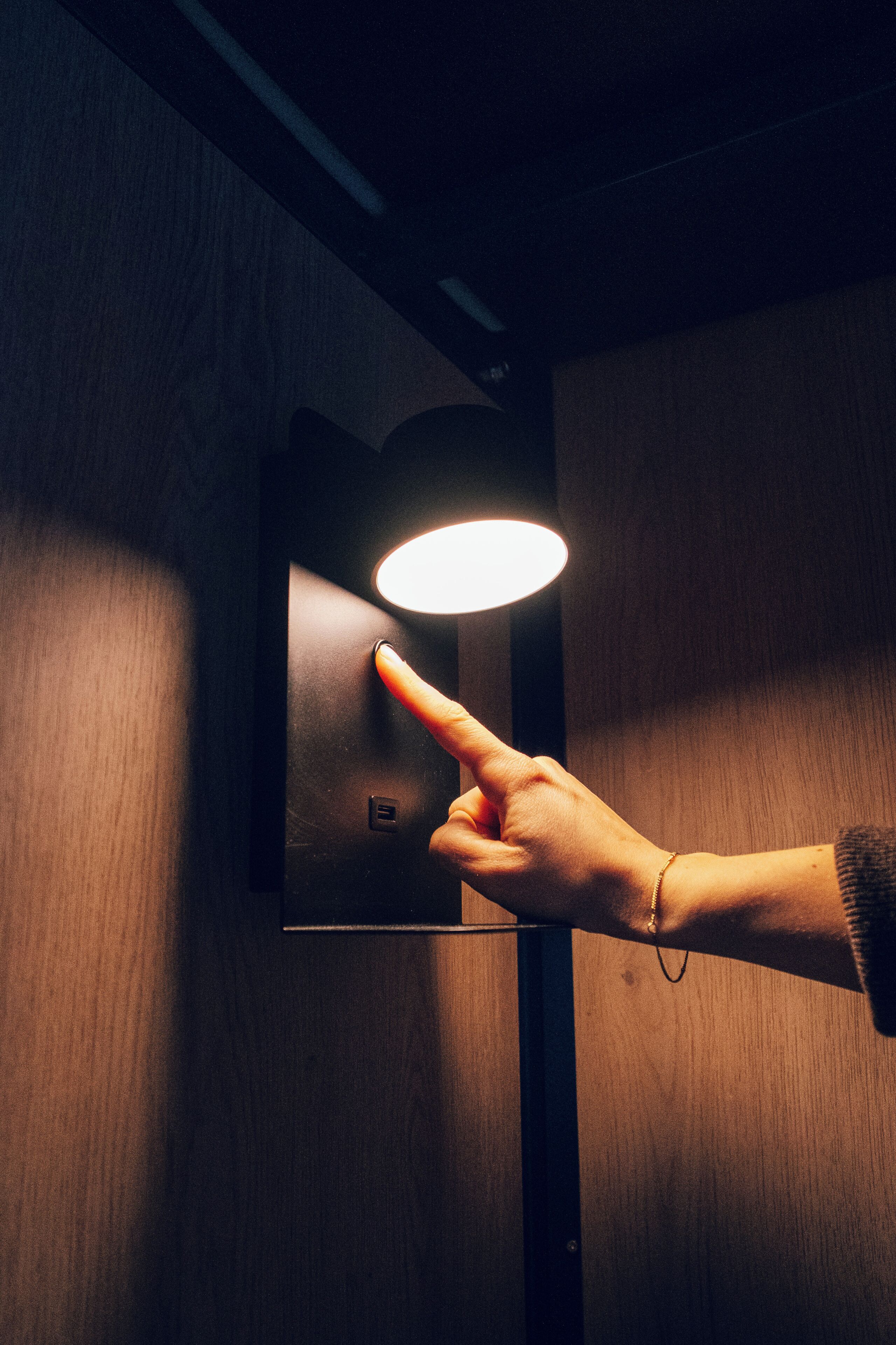 En hånd trykker på en knap på en vægmonteret lampe.
