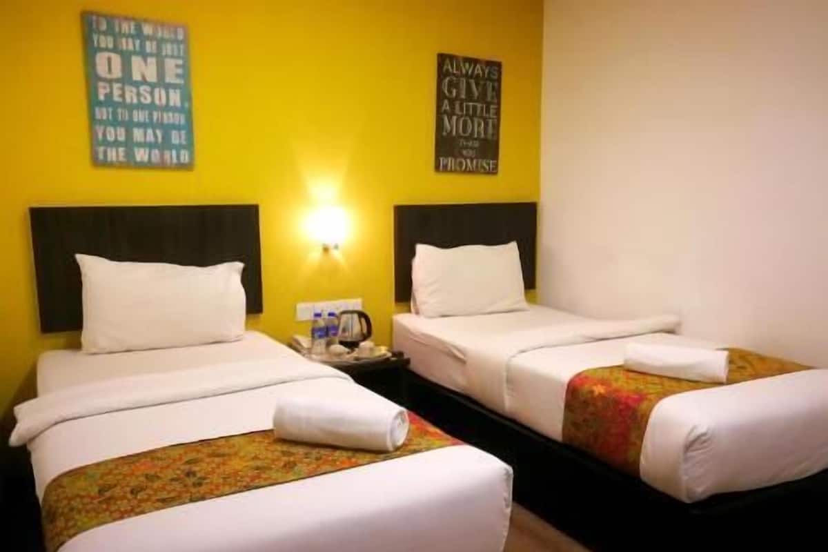 Une chambre d’hôtel avec deux lits, une table de chevet avec une lampe et des affiches motivantes accrochées aux murs.