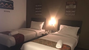 Zwei Einzelbetten mit weißen Leinen, eine an der Wand befestigte Lampe und motivierende Poster.