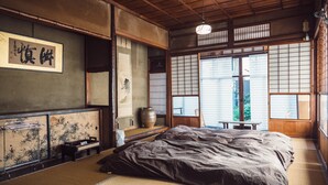 Um quarto japonês tradicional com tatames, futon, portas deslizantes shoji e vista para o exterior.