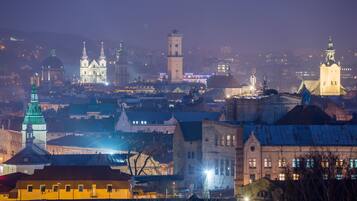 A historic cityscape at dusk with illuminated buildings and a prominent tower.
