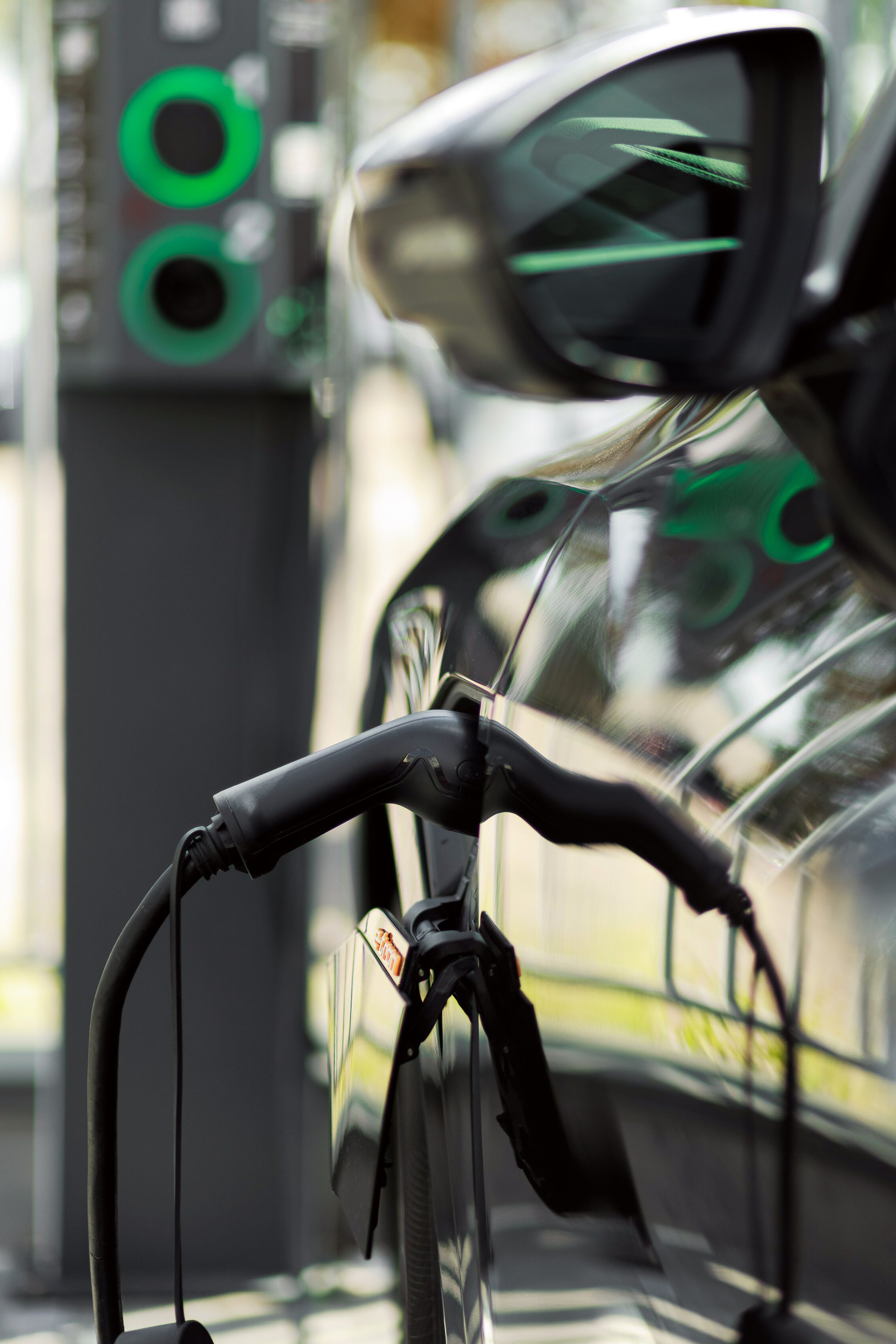 Un gros plan du guidon et du rétroviseur d’un vélo, avec une voiture et des feux de signalisation en arrière-plan.