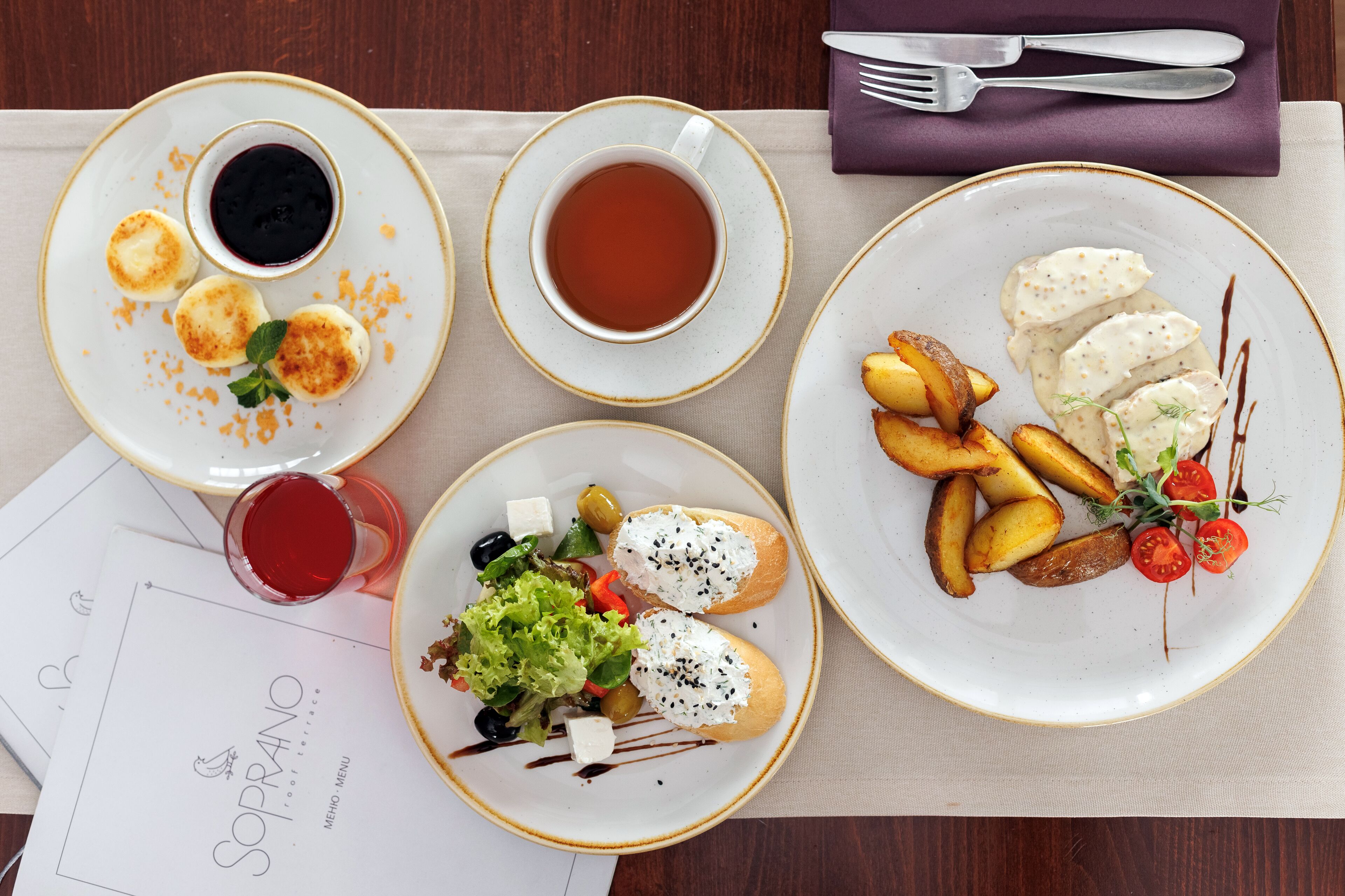 A table set with plates of food, a menu, and cutlery.