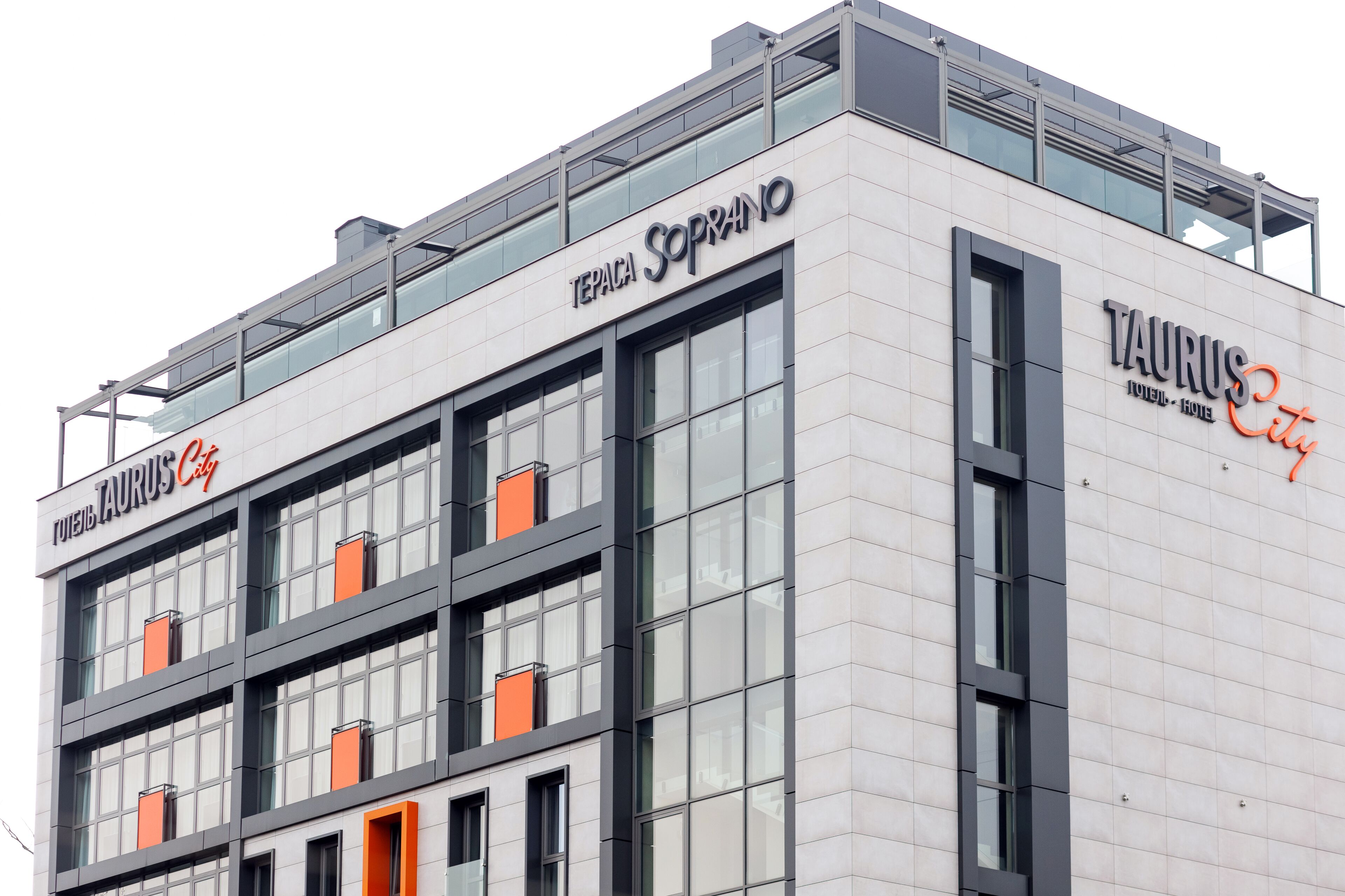 A modern building with the name "TAURUS City Hotel" and "TERPACA SOPRANO" on the facade.