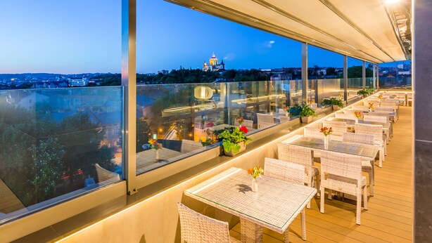 A rooftop terrace with glass balustrades, wicker furniture, and potted plants. - Taurus City (Lviv)