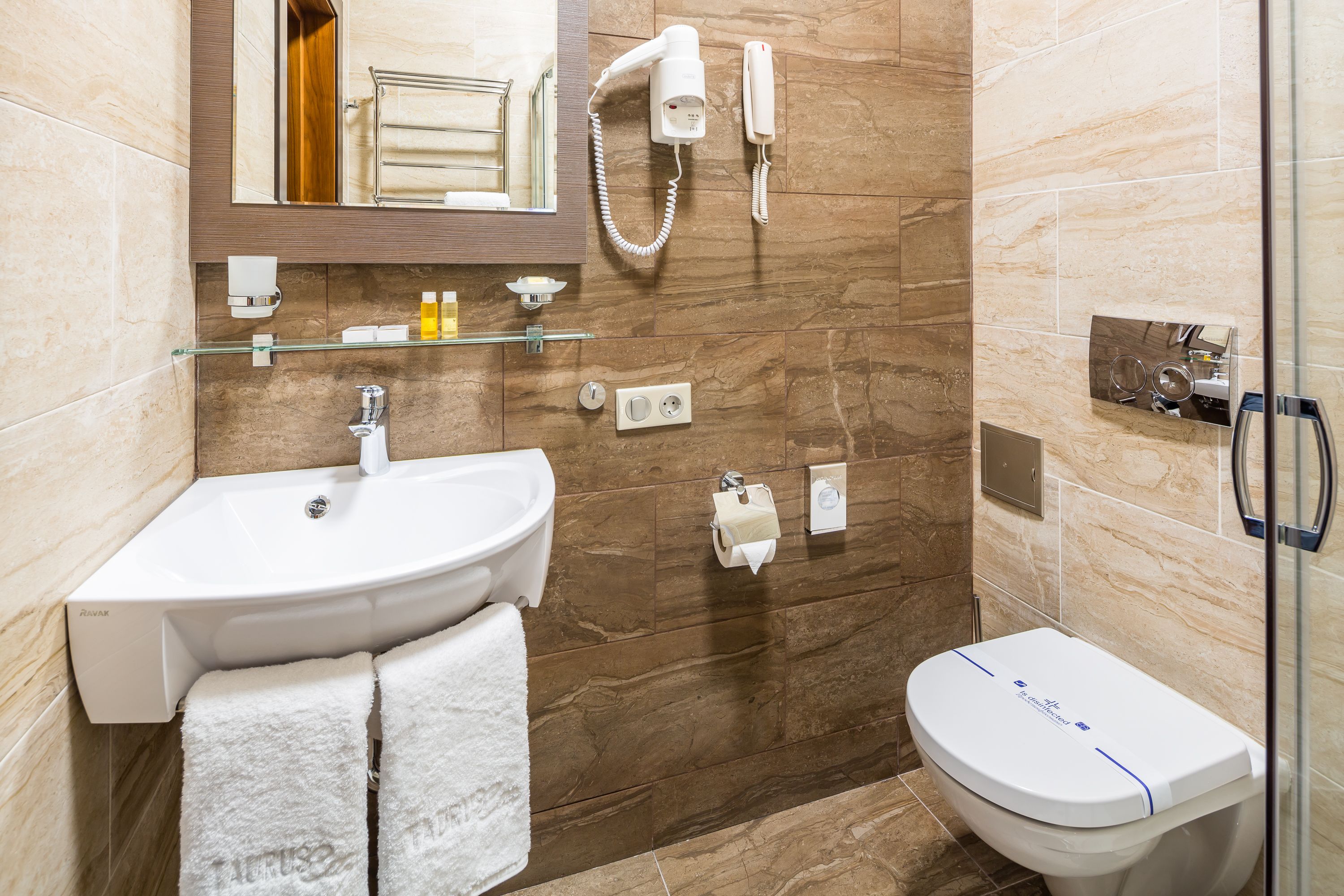 A modern bathroom with a white sink, a toilet, a glass shower enclosure, and a mirror above the sink.