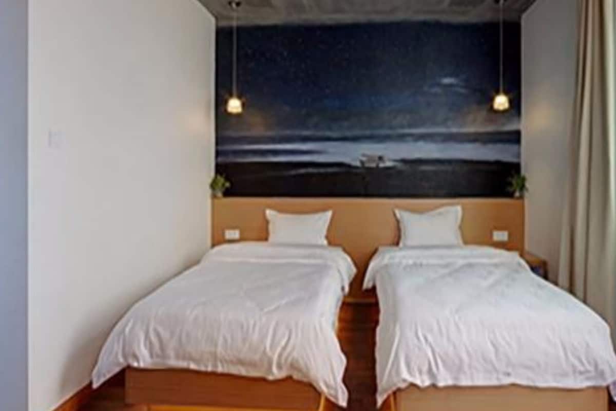 A bedroom with two beds, a night sky mural on the wall, and a wooden floor.
