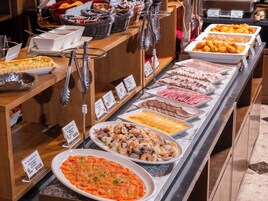 Un bufé con diversas opciones de comida, incluyendo mariscos, carnes y ensaladas.