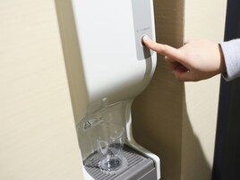 Una mano preme un pulsante su un distributore d'acqua.