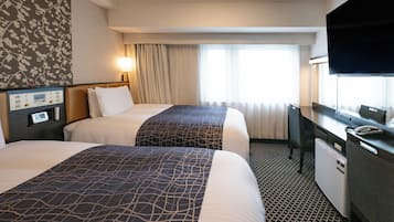 Et hotelværelse med to senge, et skrivebord med et fjernsyn og en minibar.