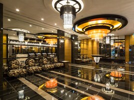 A lobby with a checkered floor, seating area with patterned chairs, and a bar with a reflective surface.