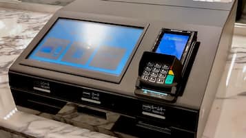 Mostrador de recepción de hotel con pantalla digital, lector de tarjetas y estación para llaves de habitación.