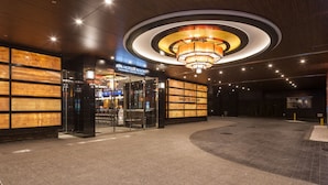 A modern hotel entrance with a circular light fixture, glass doors, and a sign reading "APA HOTEL & RESORT". - APA Hotel & Resort Nishishinjuku Gochome Ekimae Tower (Tokyo)