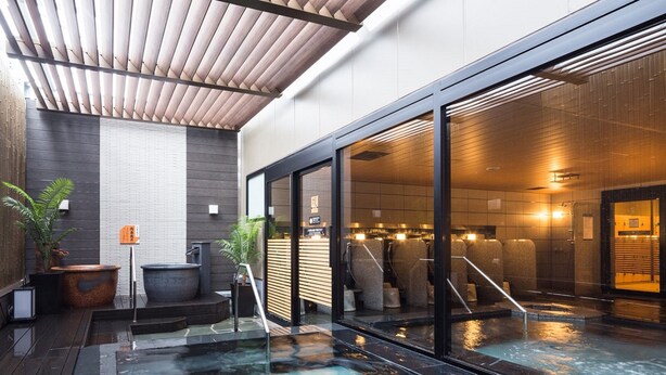 A modern indoor pool area with a wooden ceiling, large windows, and a seating area with a hot tub. - APA Hotel & Resort Nishishinjuku Gochome Ekimae Tower (Tokyo)
