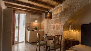 Uma cozinha acolhedora com vigas de madeira, parede de pedra e um espaço de refeições com cadeiras e mesa.