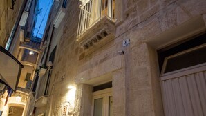 Uma rua estreita com edifícios de pedra, uma porta visível e um poste de luz.