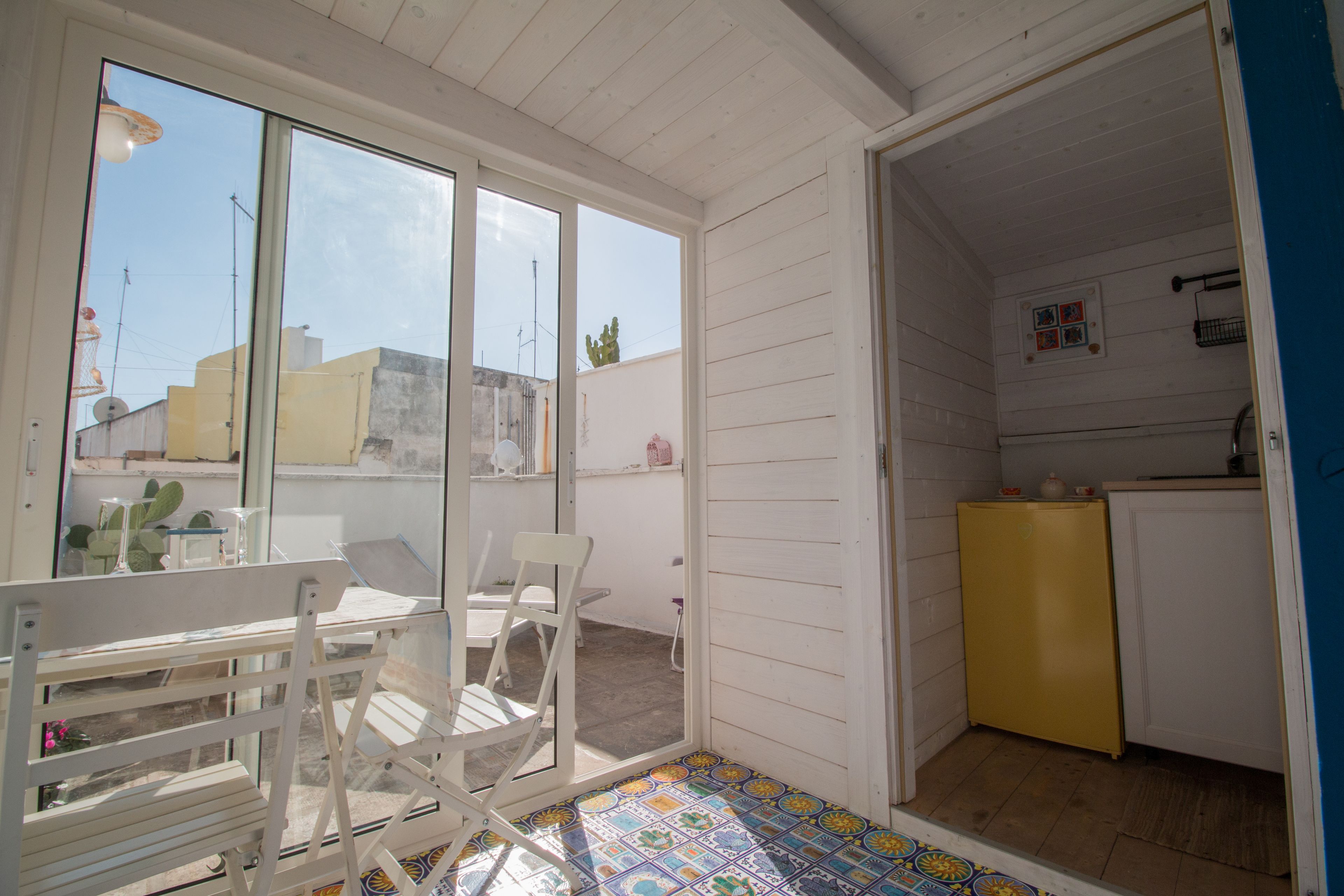 A small, open-plan room with a dining area, a kitchen, and a view through large windows.