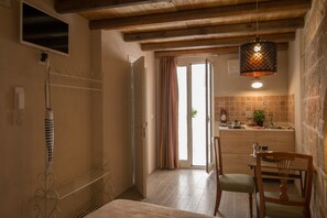 A cozy kitchen with wooden beams, a dining area with chairs, and a view to the outside.