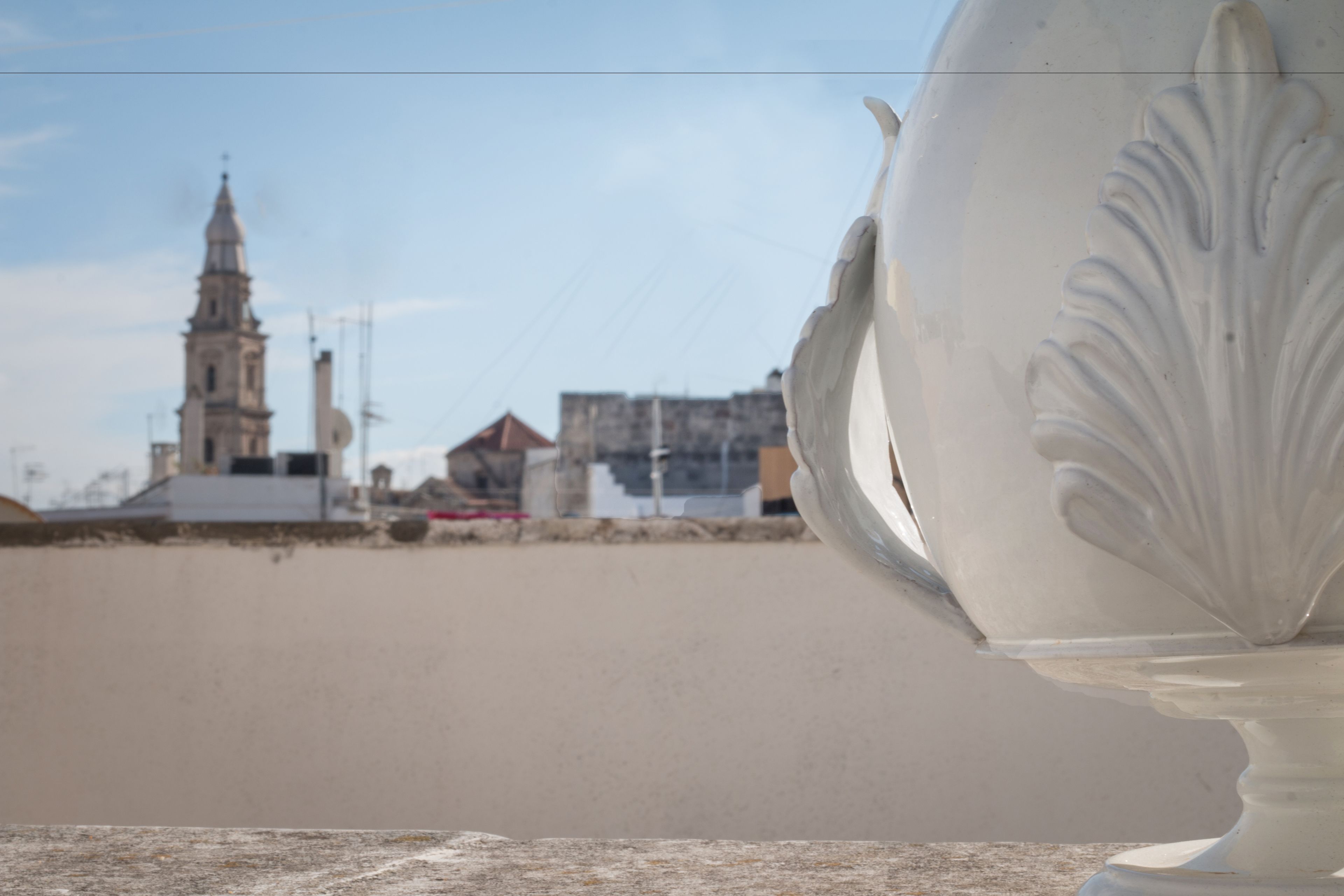 A white ceramic vase with a leaf design, placed on a stone surface.