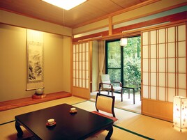 Um quarto japonês tradicional com tatames, uma mesa baixa com duas xícaras, uma cadeira e uma porta deslizante que dá para um jardim.