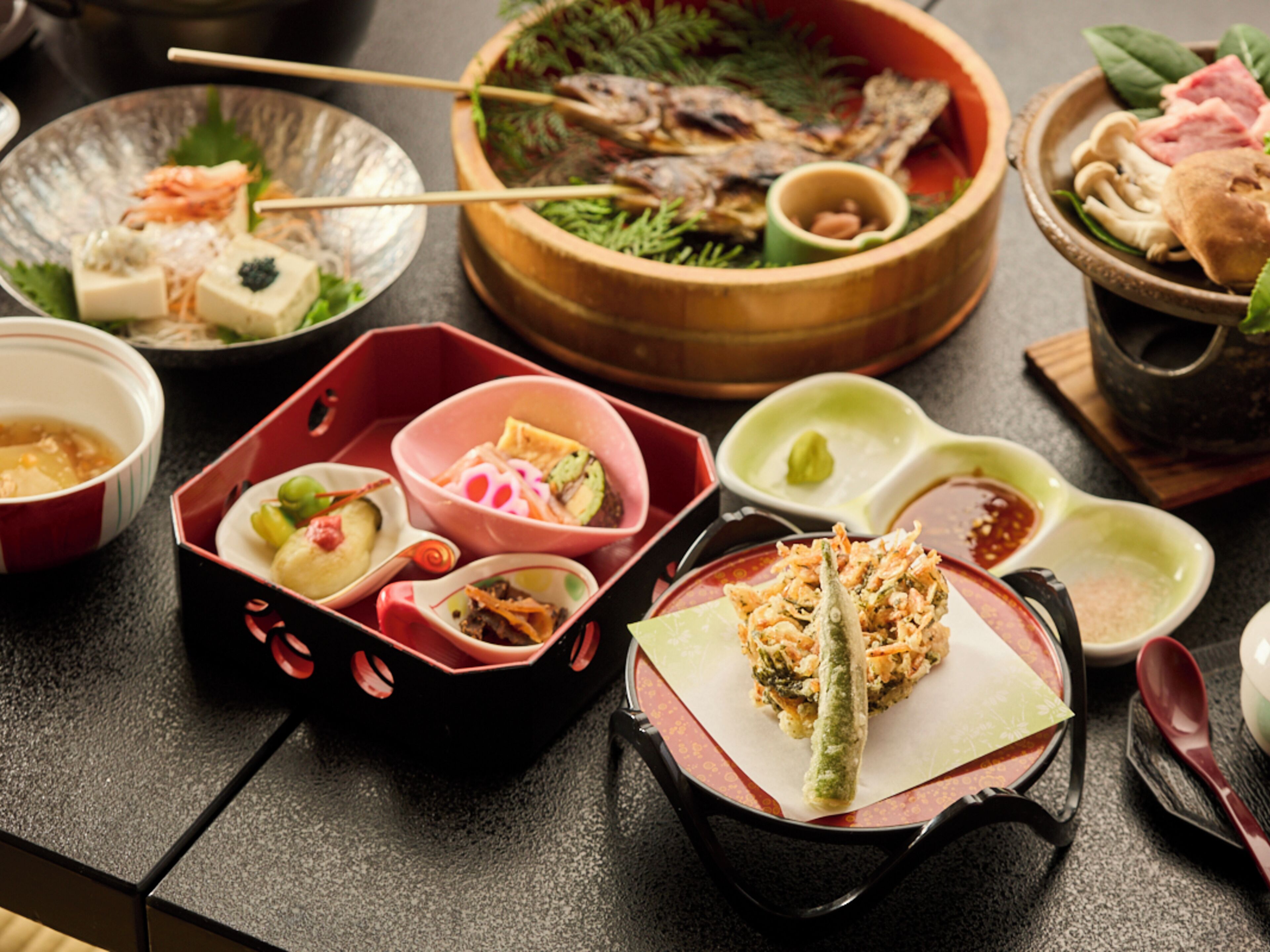 Una variedad de platos sobre una mesa, incluyendo sushi, sashimi y otras opciones de cocina asiática.