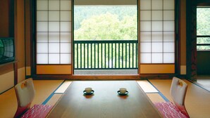 Una tradizionale stanza giapponese con pavimenti in tatami, paraventi shoji e vista su una zona boschiva.