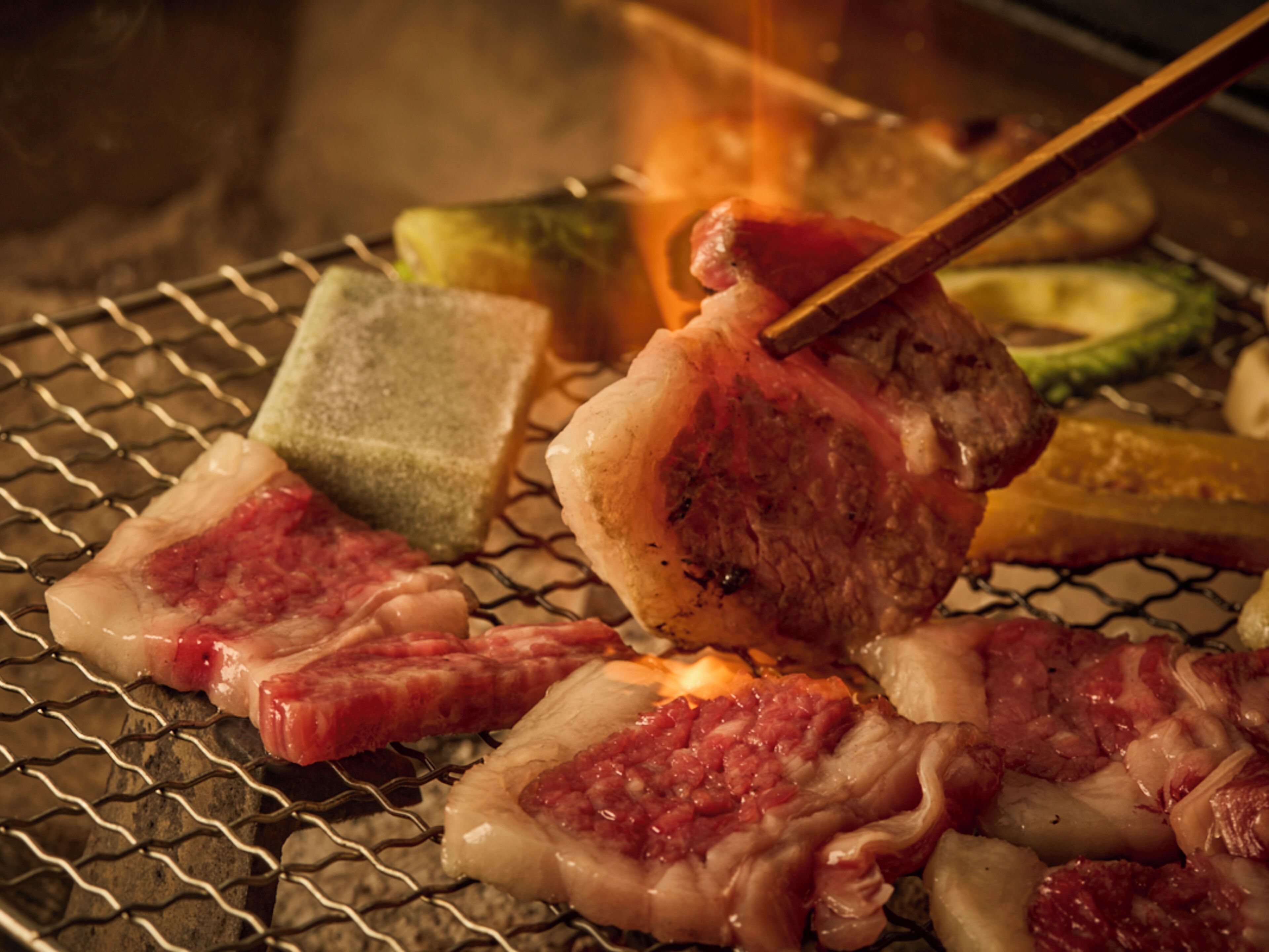 Uma churrasqueira com diversos tipos de carne e vegetais sendo preparados.