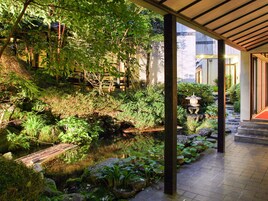Um jardim tranquilo com um pequeno lago, uma ponte de bambu e lanternas japonesas tradicionais.
