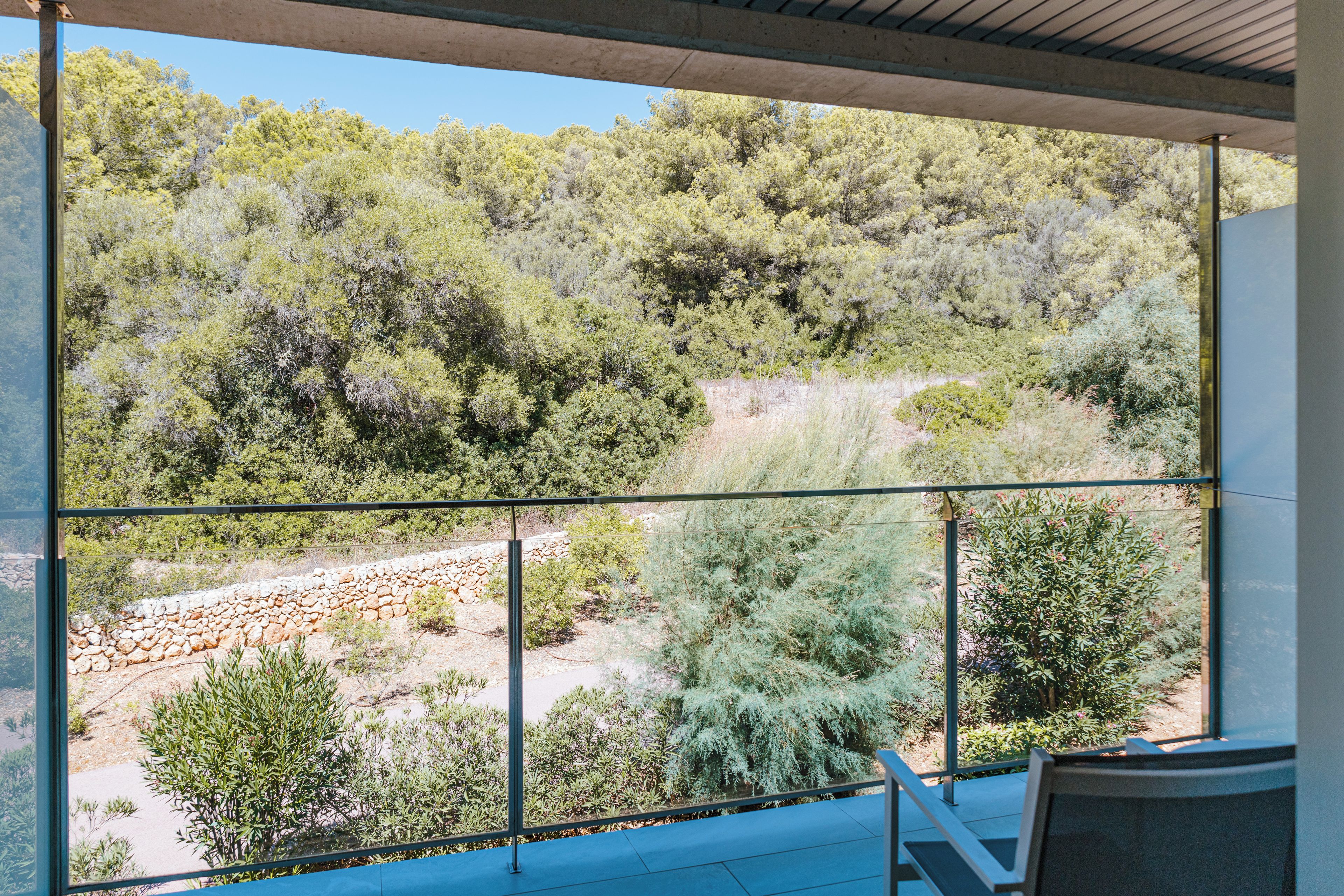 Ein Balkon mit Blick auf felsiges Gelände und dichtes Grün.