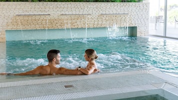 Une piscine intérieure avec un mur en briques et un sol carrelé.