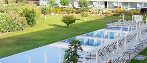 A hotel with a pool area, sun loungers, and a building with multiple floors and balconies.