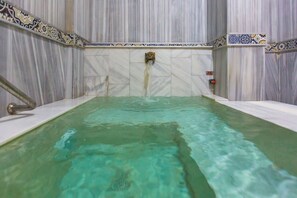 A spa area with a marble wall and a tiled floor.