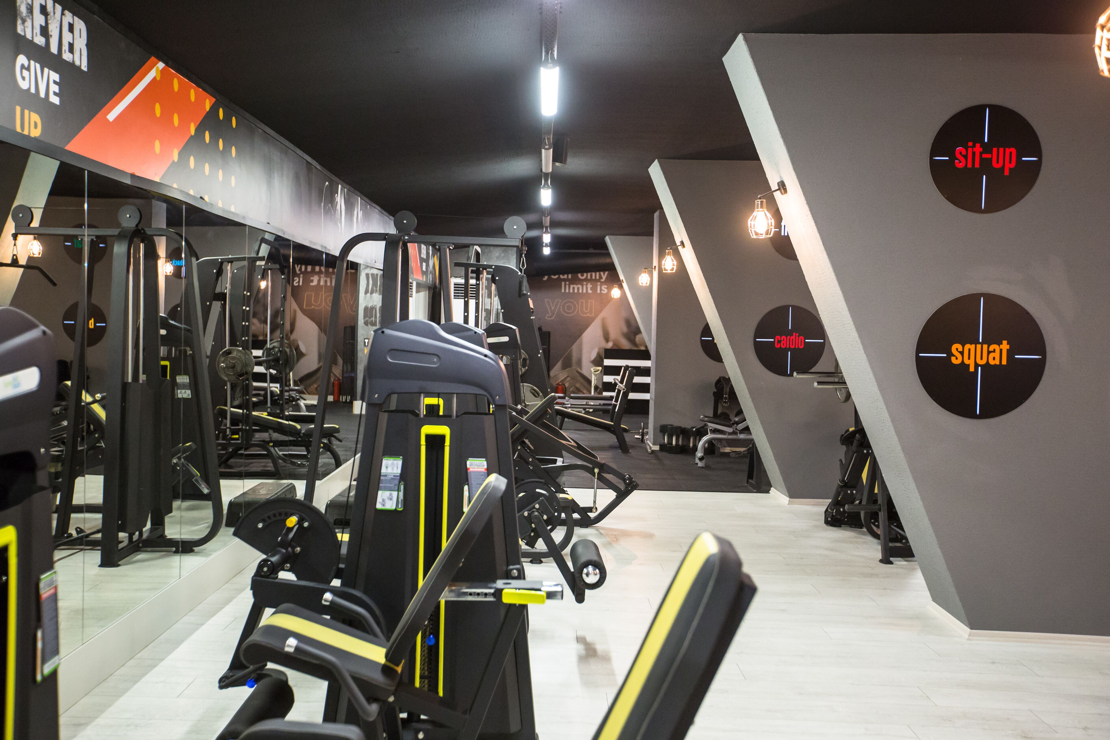 Un gimnasio con diversas máquinas de ejercicio, gráficos motivacionales en la pared y un diseño limpio y moderno.