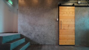 A staircase leading to a wooden door with a handle, against a textured wall. - Jellyfish Hostel (Pattaya)