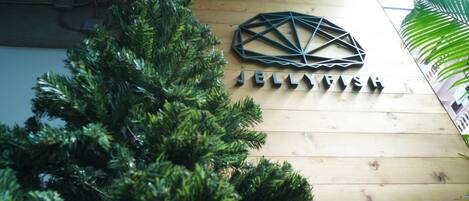 Un mur en bois orné d’une sculpture métallique aux motifs géométriques, sur lequel on peut lire le nom « JELLYVISH » en lettres noires.