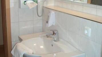 A bathroom with a white sink, mirror, and towel rack.