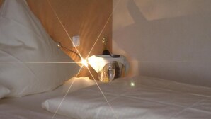 Una habitación de hotel con una cama, una mesita de noche, una lámpara y una botella de agua.