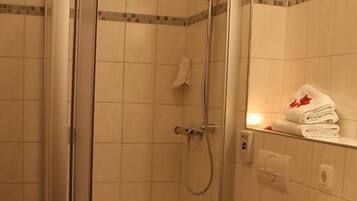 Une salle de bain avec une douche à parois de verre, des toilettes et un lavabo équipé d’un porte-serviettes.