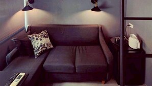 A compact hotel room with a bunk bed, a sofa, bedside lamps, and a bedside table with a lamp and a phone. - Inner Place (Tainan)