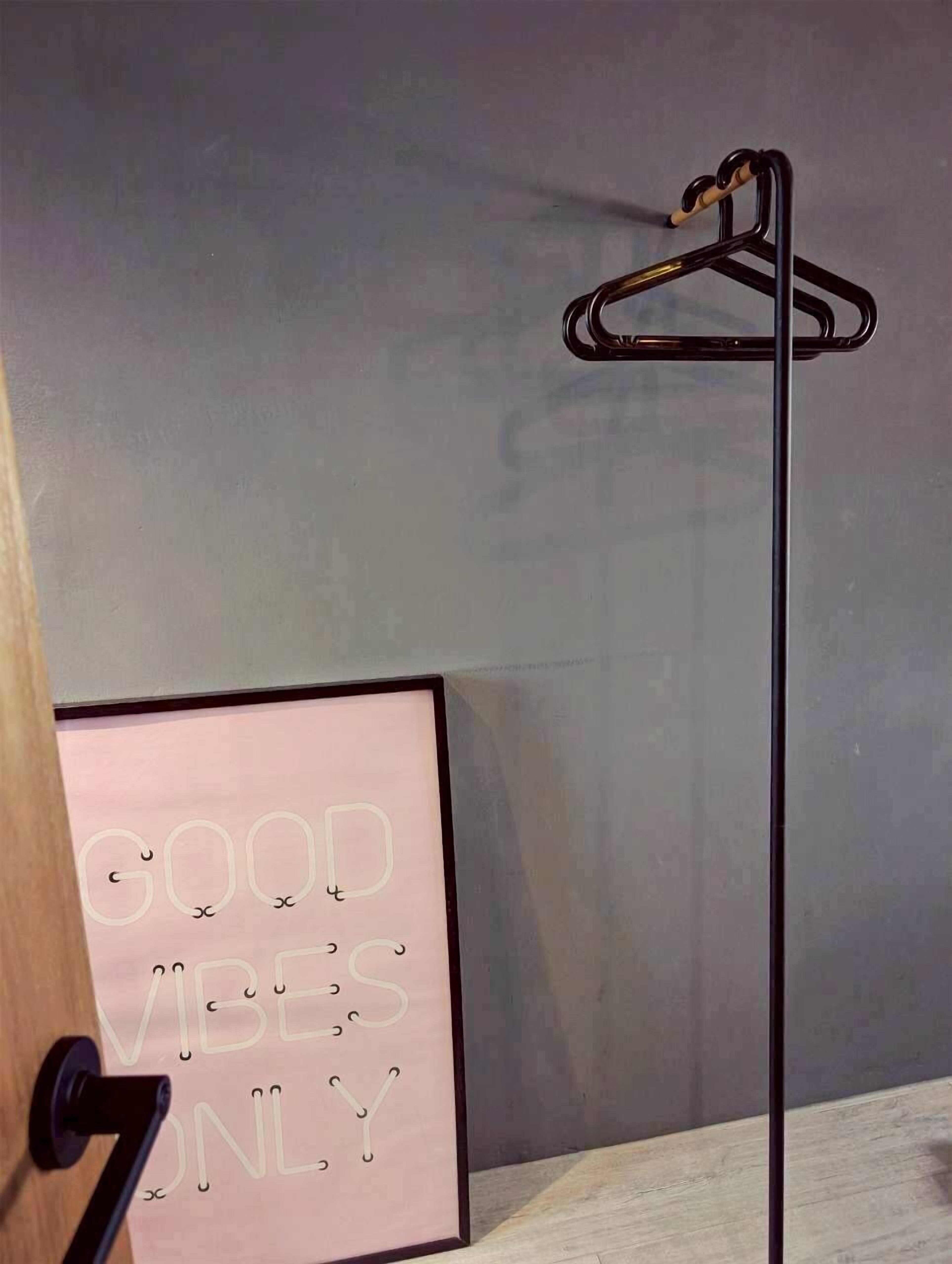 A framed sign with the text "GOOD VIBES ONLY" and a black metal hanger on a wall.