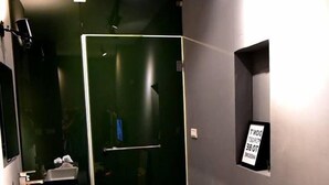 A modern bathroom with a glass shower enclosure, a sink, and a mirror. - Inner Place (Tainan)