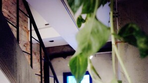 A staircase with a metal railing, a brick wall, and a window with blinds. - Inner Place (Tainan)